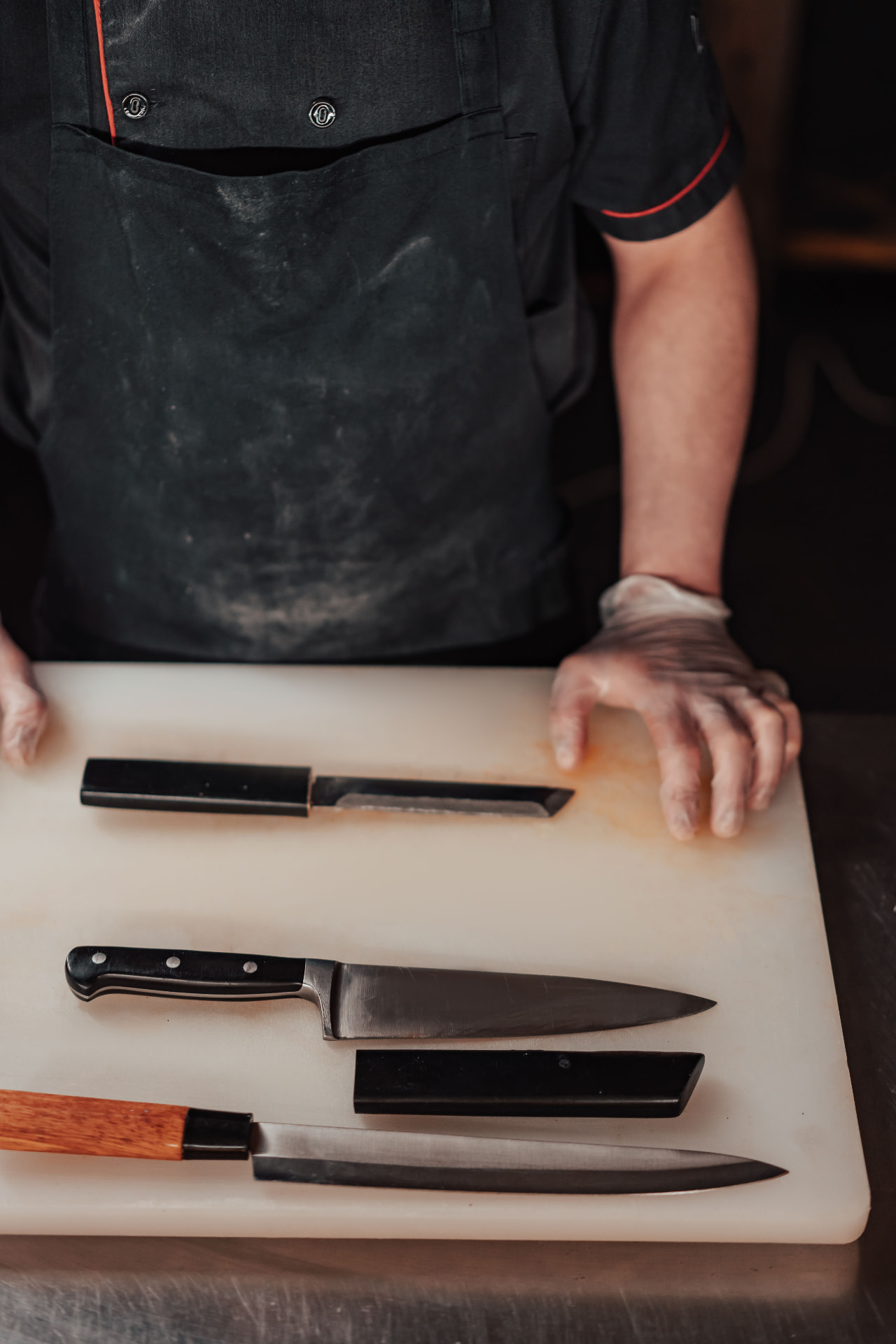 Küchenmesser auf einem Schneidebrett neben den Händen eines Kochs